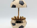 une image représentant un pot de fleurs en forme de ballon de football noir et doré sur fond blanc