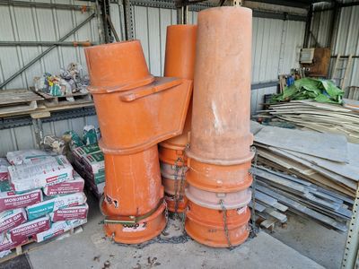 trois tuyaux orange empilés les uns sur les autres dans un entrepôt