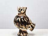 une figurine de chouette posée sur une table blanche