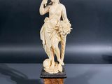 an antique carved ivory figurine of a woman holding a flower