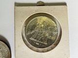 a silver coin sitting next to a silver coin on a white surface