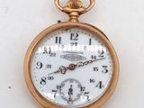 une montre de poche en or avec un cadran blanc sur une surface blanche