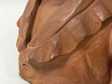 a clay bust of a man on a white surface