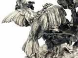 a silver vase with a bird and flowers on it