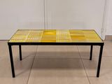table basse carrelée jaune et noire, avec des pieds noirs