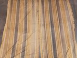 une jupe rayée beige et noire posée par terre