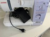 a white sewing machine sitting on a table with a power cord