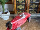 a red toy car sitting on a table next to a potted plant