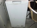 a small white refrigerator in a kitchen next to a table and chairs