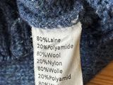 a label on a blue sweater that is on a wooden table
