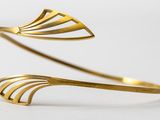 a close up of a pair of gold cuff bracelets on a white surface