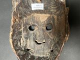 an image of a wooden mask on a table with a tag on it