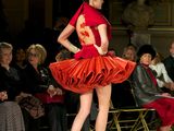 a woman that is walking down the runway in a red dress