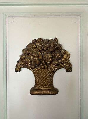 un vase en or avec des fleurs accroché au mur de la pièce