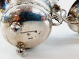 pair of silver plated teapots sitting on a white surface