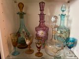 de nombreux vases en verre de différentes couleurs posés sur une étagère en verre