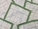 many white napkins with green trims on a table