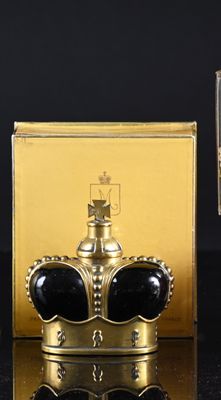 a gold box with a crown on it next to a glass