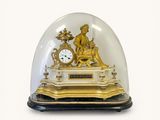 a gold clock under a glass dome on a table