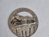 a silver coin with a train on it on a white surface