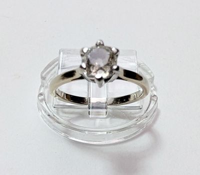 une bague ornée d'un diamant posé sur une monture transparente