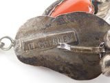 a close up of a silver broochee with an orange stone