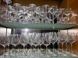 many wine glasses stacked on a glass shelf in a cabinet