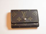 Portefeuille Louis Vuitton posé sur une surface blanche, sur fond blanc