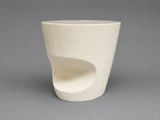 a white cup that has a curved design on it