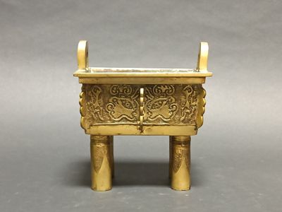 an image of a small brass incense box on a grey background