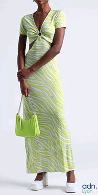 woman in a yellow and white dress holding a green purse