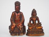pair of bronze statues of buddhas sitting on top of a table