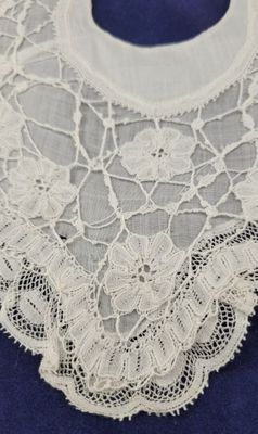 un gros plan sur un col en dentelle blanche sur fond bleu