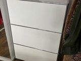 a white chest of drawers in the corner of a room
