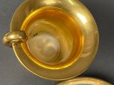 a gold tea cup and saucer with a green and white plate