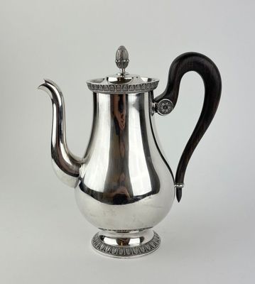 une théière ancienne en argent avec une anse noire sur fond blanc