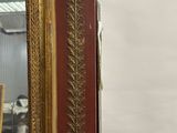 an antique gold framed mirror with a red frame and gold trim
