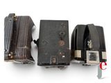 three old cameras sitting next to each other on a white surface