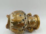 a gold and white vase sitting on a white surface