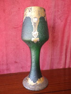 a green and gold vase on a wooden table