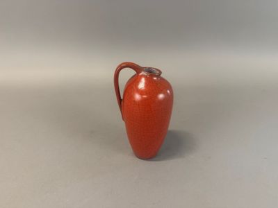 a small red vase with a handle on a table
