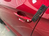 a ruler on the door handle of a red car