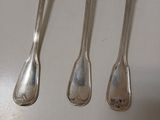 quatre cuillères en argent sont alignées sur une surface blanche