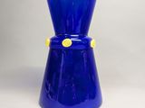 un vase en verre bleu orné d'un bouton jaune