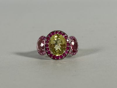 a ring with a yellow and pink stone surrounded by pink sapphires