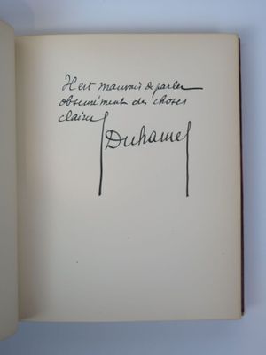 un livre ouvert, sur lequel on distingue une écriture, posé sur une table