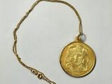 a close up of a gold coin with a chain on a white surface