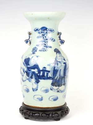 un vase bleu et blanc posé sur un socle, sur une surface blanche