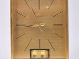 a gold clock sitting on top of a white table