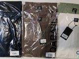 trois paires de chemises pour homme dans des sacs en plastique posés sur une table